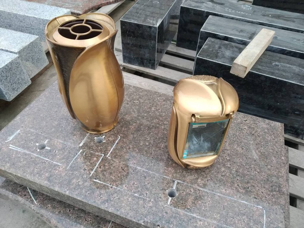 Золотисті ваза й лампада на гранітній плиті перед монтажем.