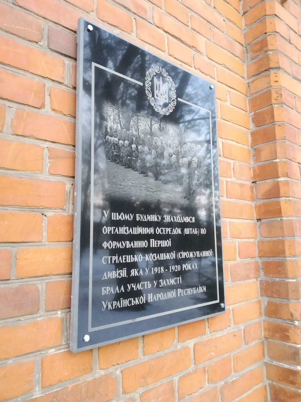 Історична меморіальна дошка з текстом на цегляній стіні
